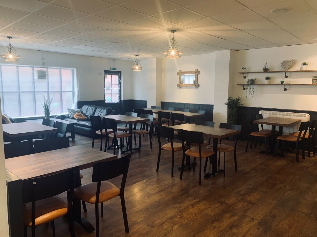 A wide view of Coast Cafe's wooden tables, navy panelling and pendant lights.